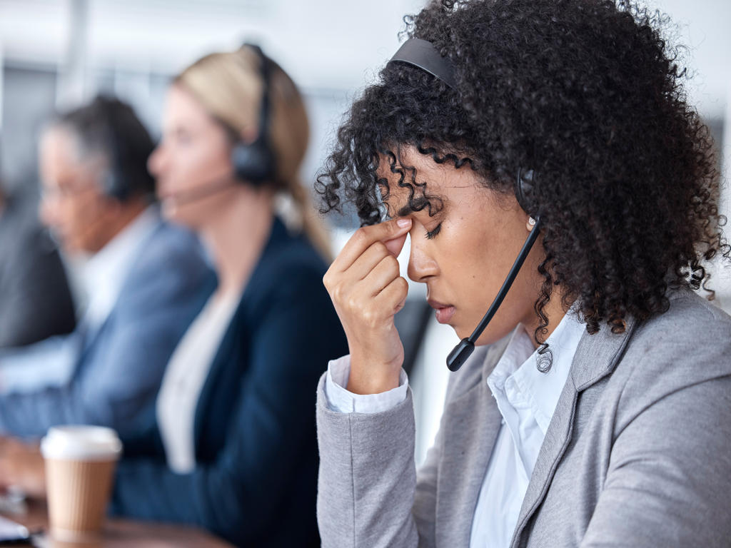 Headache, tired or woman in call center with burnout, head pain or overworked in crm communication