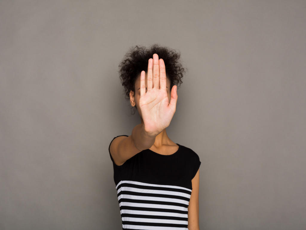 Young african-american woman covering her face with palm saying no. Girl denying proposal, making stop gesture with her hand. Studio shot, copy space